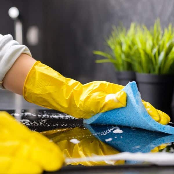 A maid wearing gloves and wiping off a countertop with a sponge during a deep cleaning by Abby's Cleaning Service